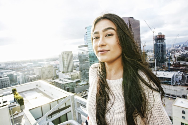 Smiling Hispanic woman posing on urban rooftop