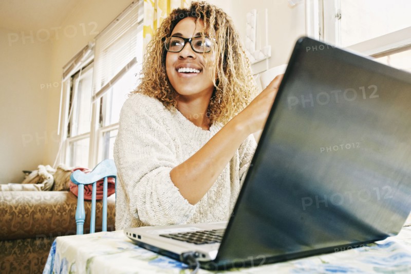 Smiling Mixed Race woman using laptop