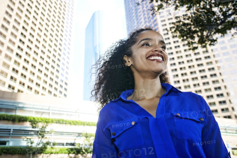 Smiling Hispanic businesswoman near highrises in city