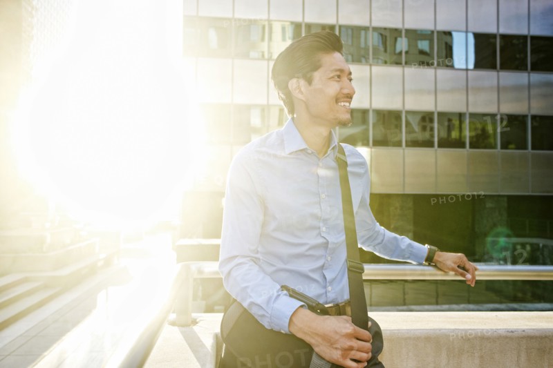 Smiling Mixed Race businessman walking outdoors on sunny day