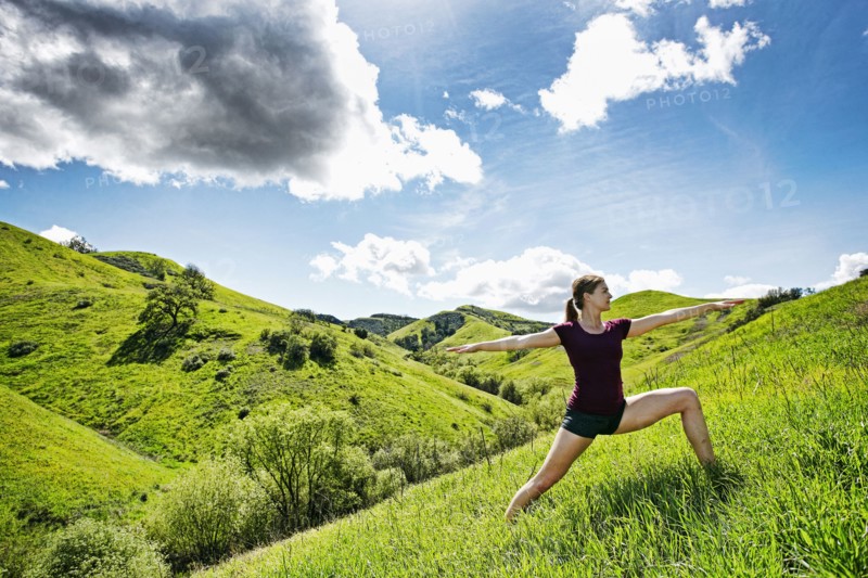 Caucasian woman doing yoga on hill