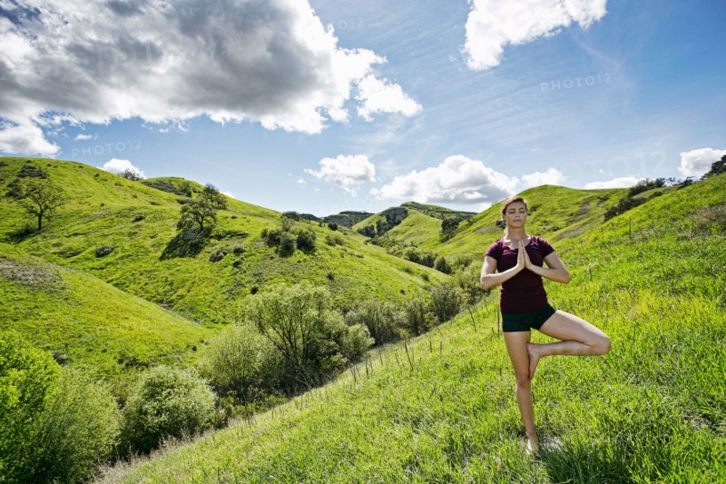 Caucasian woman doing yoga on hill