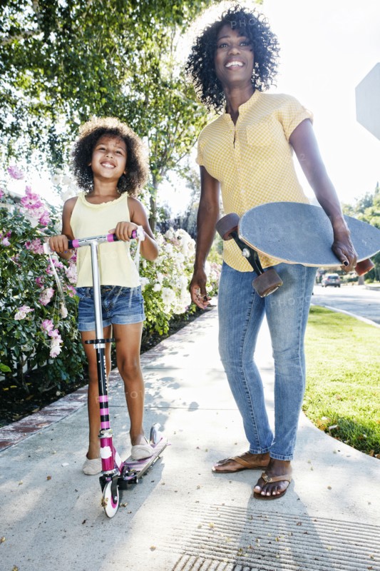 Mother and daughter posing on sidewalk