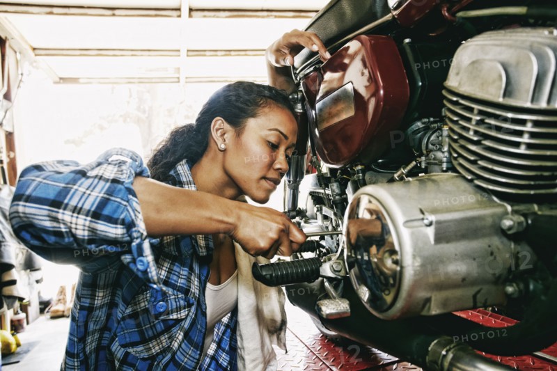 Mixed Race woman repairing motorcycle in garage