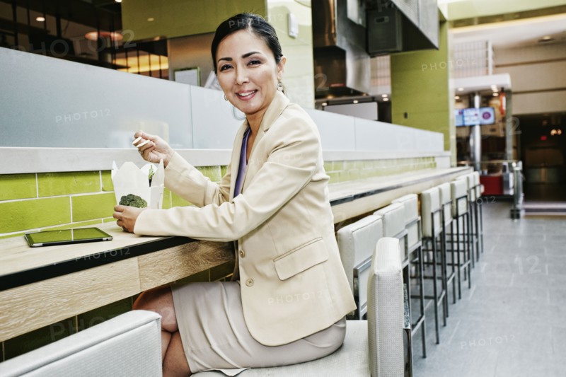 Japanese businesswoman in food court eating food from carton