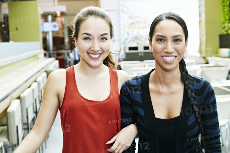 Smiling Mixed Race women posing in food court