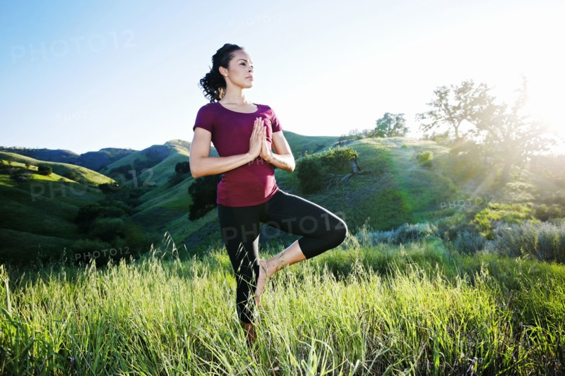 Mixed Race woman practicing yoga on hill