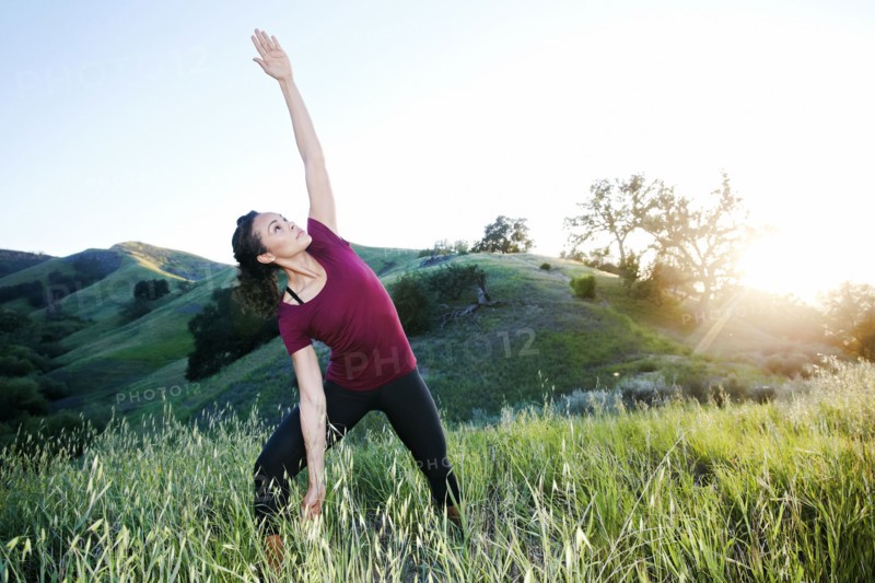 Mixed Race woman practicing yoga on hill