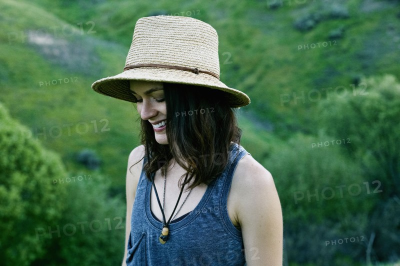 Smiling woman wearing hat on hill