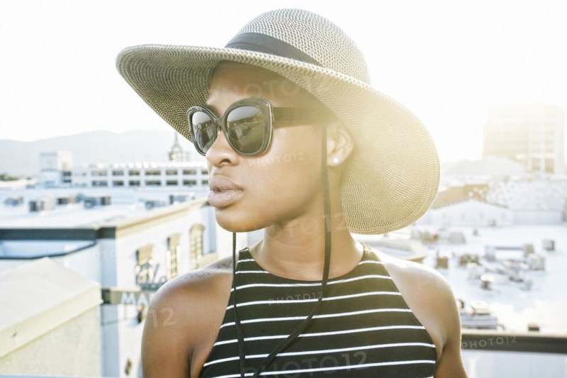 Black woman wearing sun hat and sunglasses on rooftop