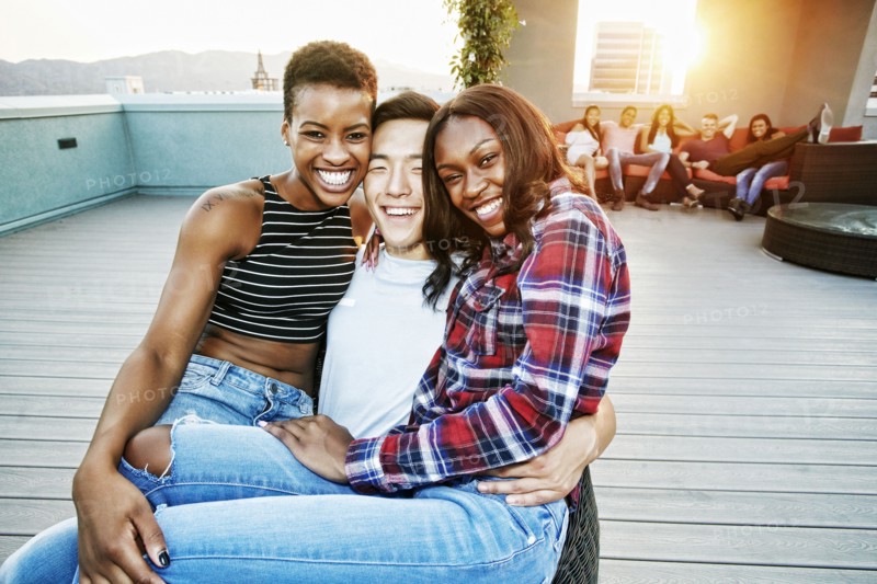 Portrait of smiling women on lap of man on rooftop