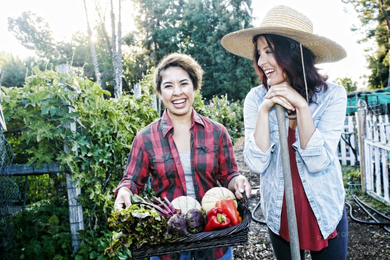 Portrait of women with basket of vegetables in garden