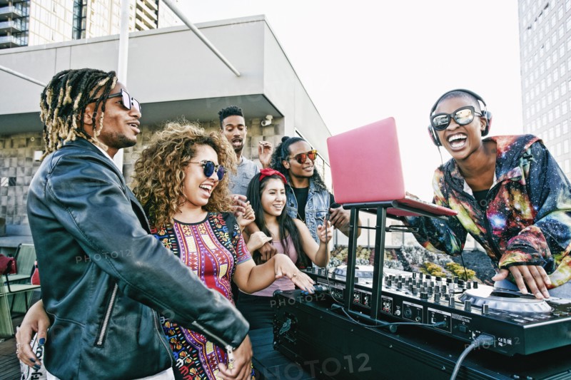 Friends smiling with DJ on urban rooftop