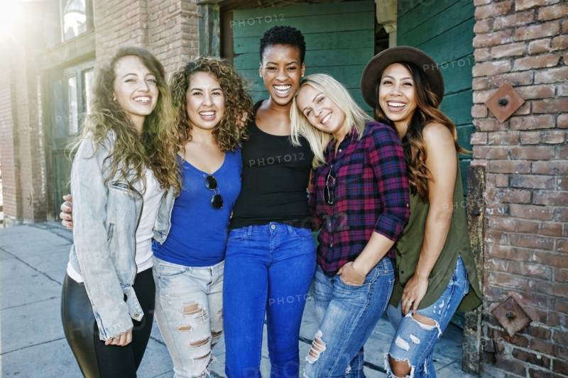 Women posing on sidewalk in city