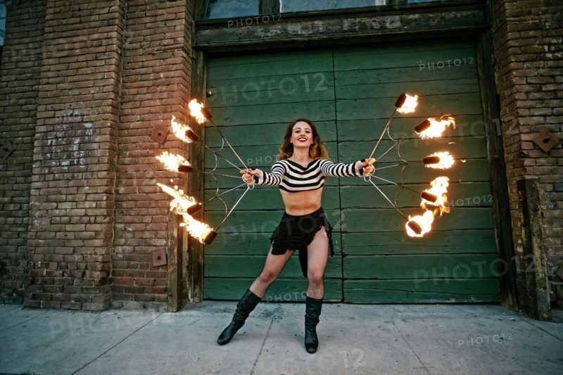 Caucasian woman juggling fire on city sidewalk