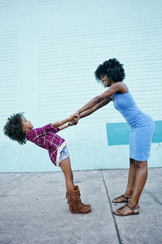 Smiling mother and daughter playing on sidewalk
