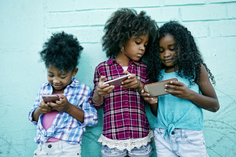 Girls leaning on wall texting on cell phones