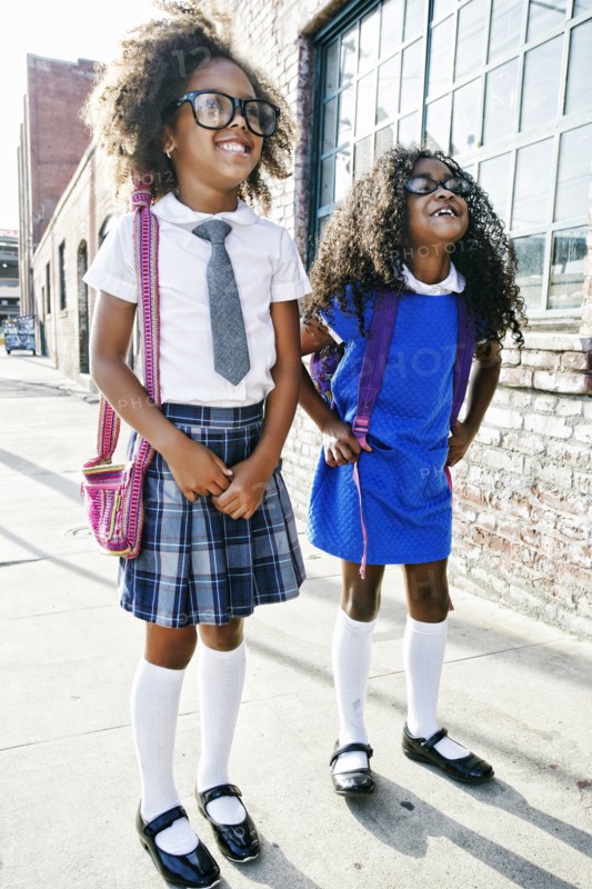 Smiling girls standing on sidewalk ready for school