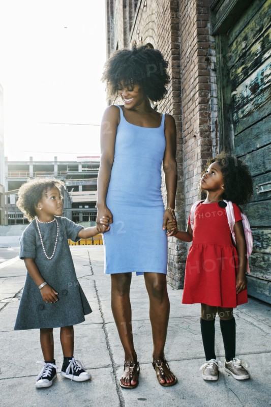 Smiling mother and daughters standing on sidewalk