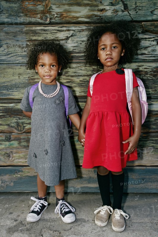 Portrait of serious girls standing near wooden wall