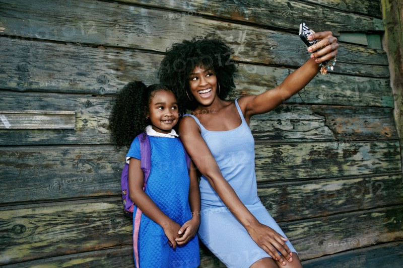 Black mother and daughter posing for cell phone selfie