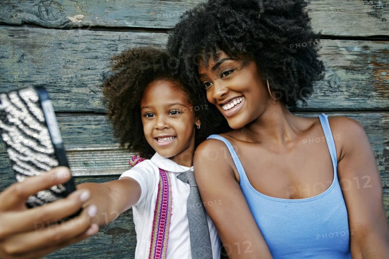 Smiling mother and daughter posing for cell phone selfie
