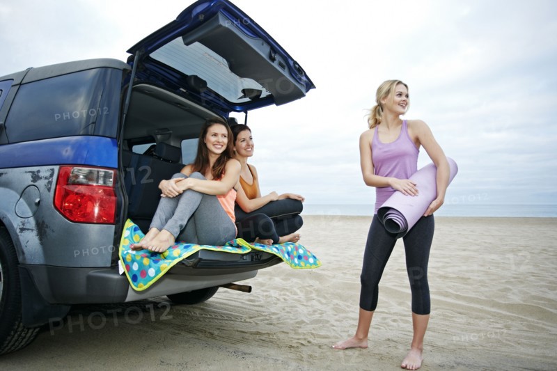 Smiling Caucasian women on beach with car