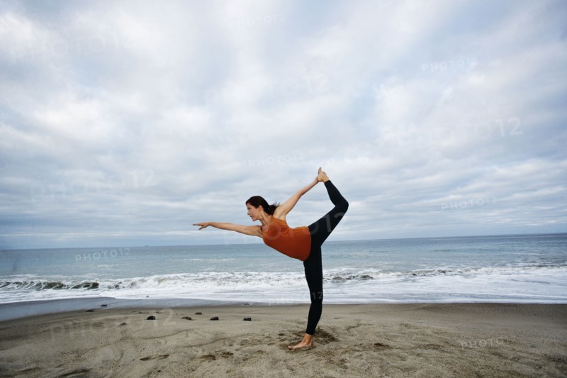 Caucasian woman performing yoga on beach