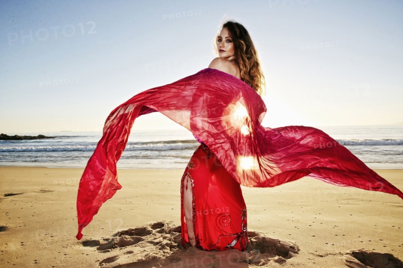 Caucasian belly dancer holding scarf on beach