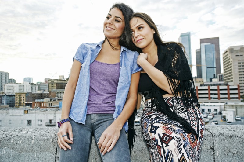 Smiling Hispanic women relaxing on urban rooftop