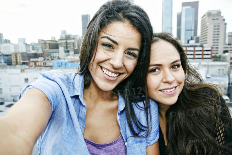 Smiling Hispanic women posing on urban rooftop