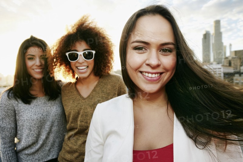 Portrait of smiling women on urban rooftop at sunset