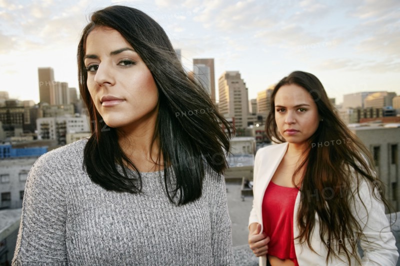 Portrait of serious Hispanic women on urban rooftop at sunset