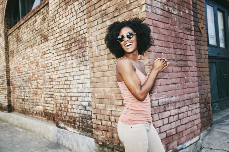 Laughing Black woman standing near corner of brick building