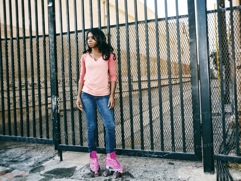 Black woman wearing roller skates near metal gate