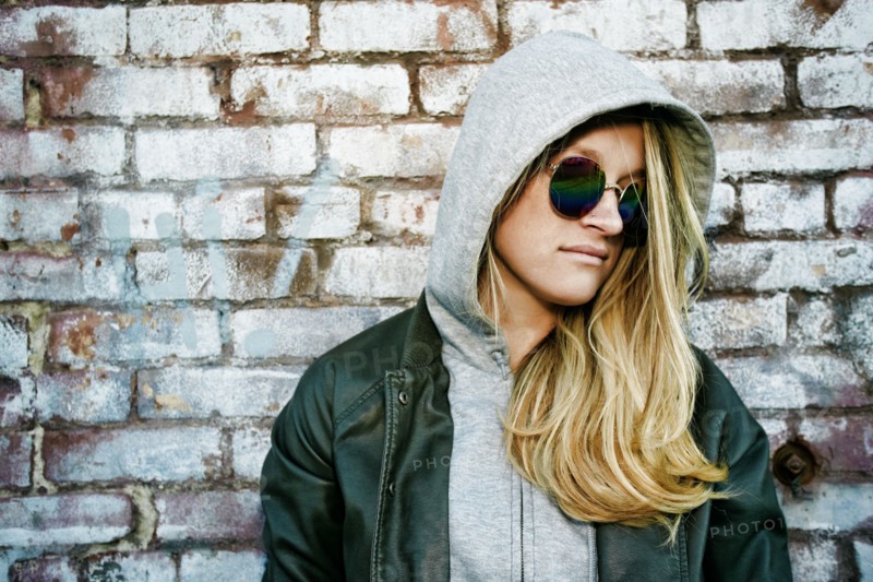 Caucasian woman wearing sunglasses near brick wall