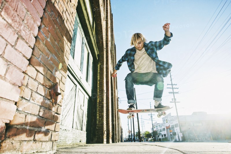 Caucasian man jumping on skateboard on urban sidewalk