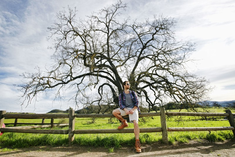 Caucasian man resting on wooden fence