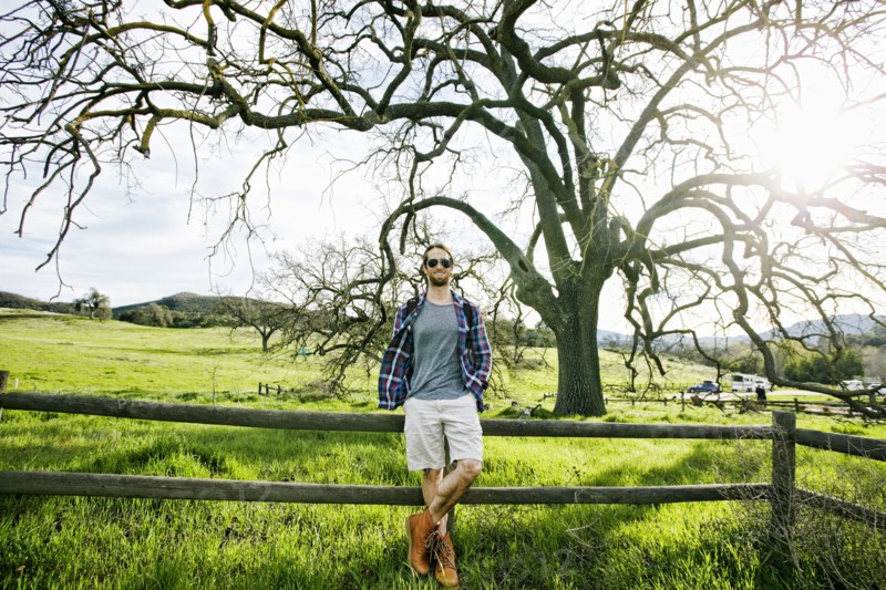 Caucasian man resting on wooden fence