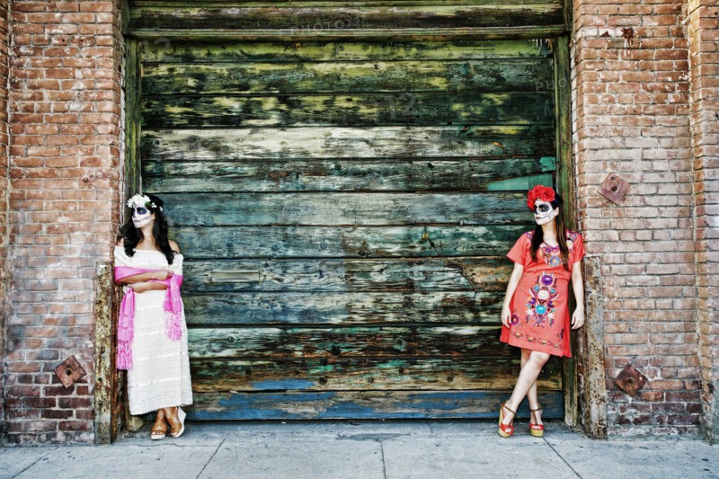 Women leaning on loading dock wearing skull face paint