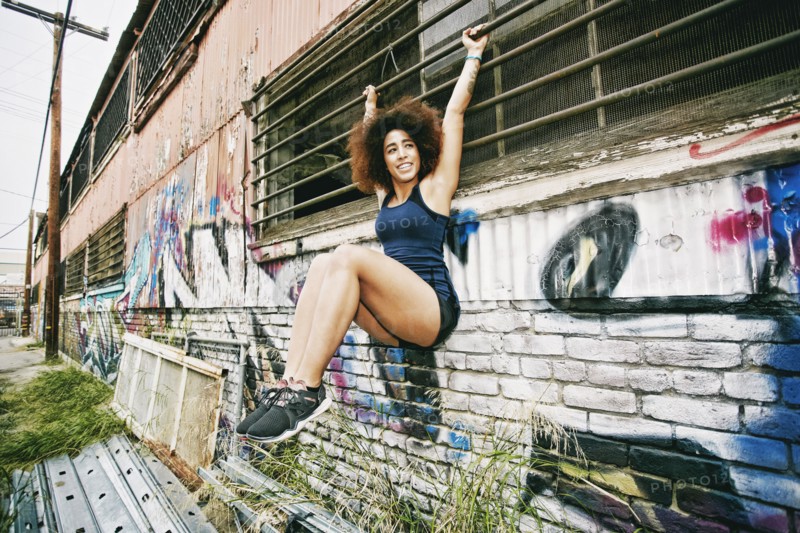 Hispanic woman hanging on bar on graffiti wall