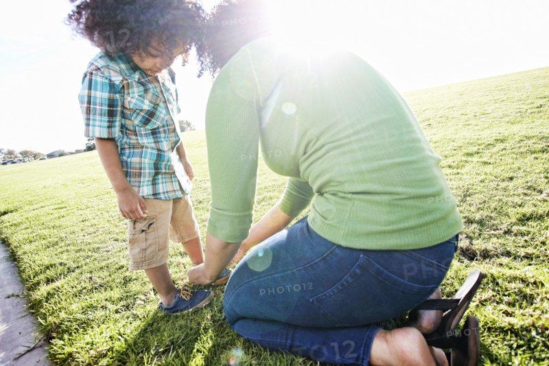 Mixed race mother tying shoe of son