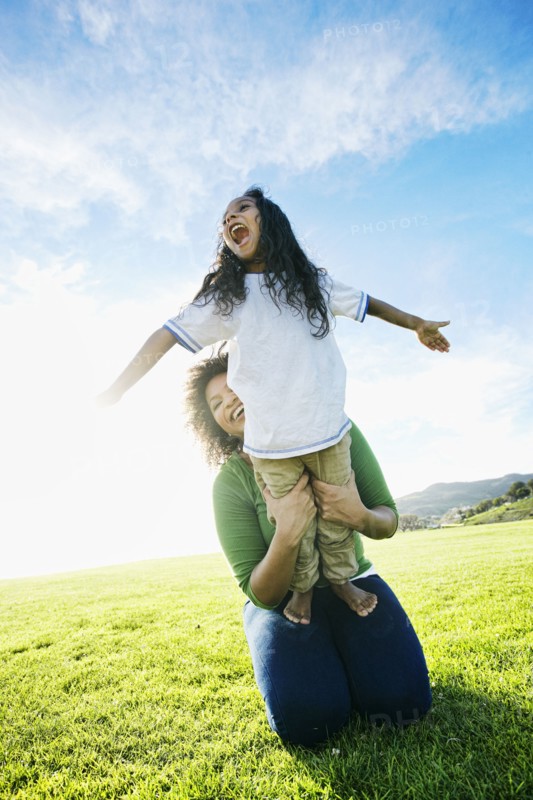 Mixed race mother holding daughter pretending to be airplane