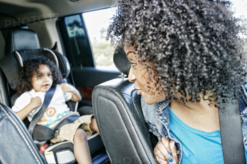 Mixed race and mother checking daughter in car seat