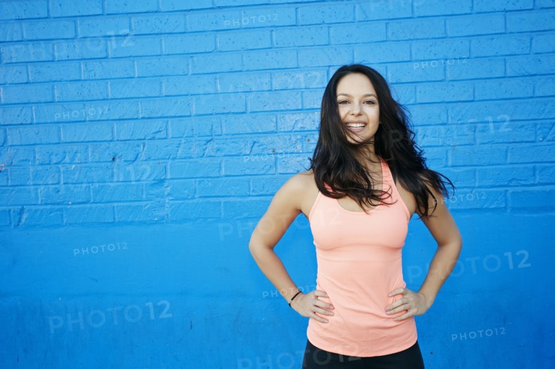 Wind blowing hair of smiling mixed race woman at blue wall