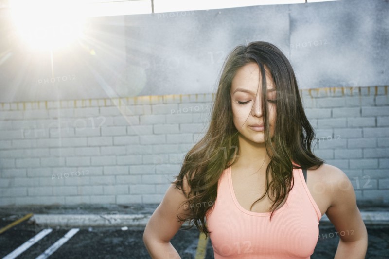 Sunbeams on mixed race woman in parking lot