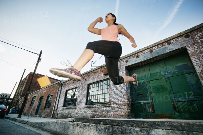 Mixed race woman jumping off loading dock