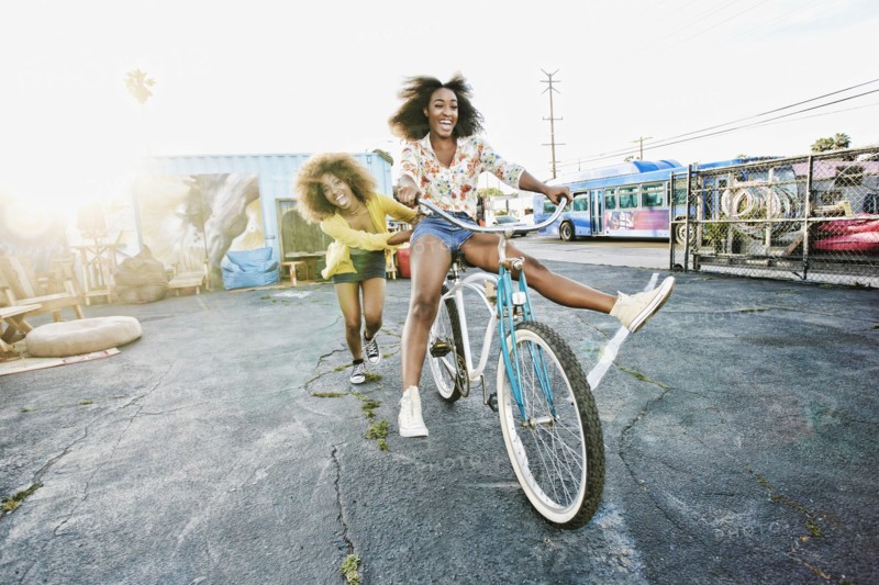 Friend pushing carefree woman on bicycle