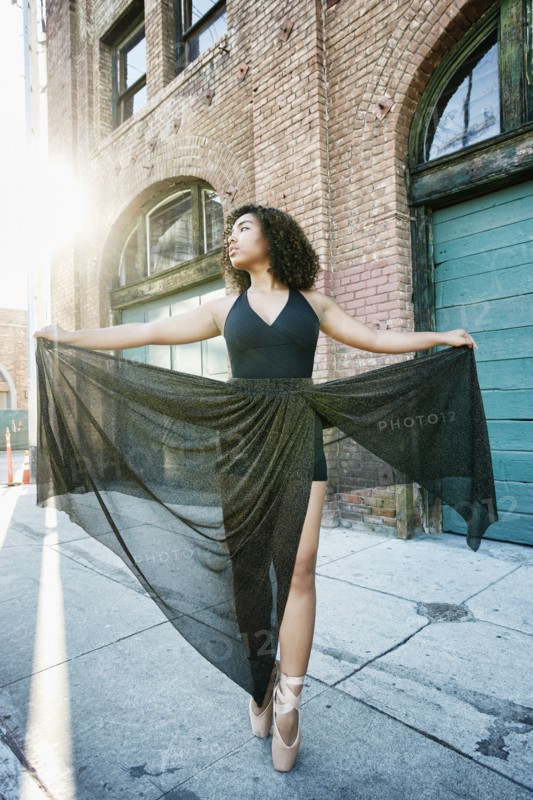 Sunbeams on mixed race woman dancing in city