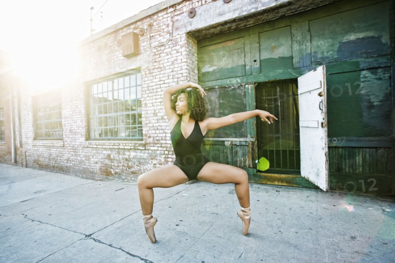 Sunbeams on mixed race woman dancing in city